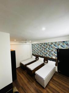 Una habitación con dos camas y una pared con un mural. en HL Residency Near Expo Mart Centre, en Greater Noida