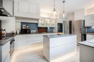 a kitchen with white cabinets and black appliances at Loch View House in Kilfinan