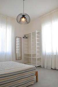 una camera da letto bianca con un letto e un lampadario di Appartamento 1m a Fiumaretta di Ameglia