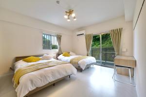 沖縄市にあるRiverside Chibana リバーサイド知花のベッドルーム1室(ベッド2台付)、窓、バルコニーが備わります。