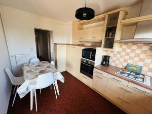 a kitchen with a table and white chairs in it at Le haie vigné in Caen