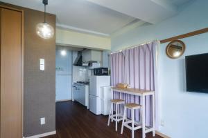 a small kitchen with a refrigerator and two stools at Sion fusaki Beachfront in Ishigaki Island