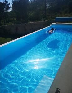 a person swimming in a blue swimming pool at NEW- Ericeira Design Villa- 10 min from Beach, pool and great view in Ericeira