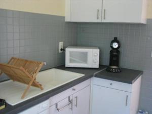 une cuisine avec un four micro-ondes et une chaise sur un comptoir dans l'établissement Maison pour 4 personnes, à Port-en-Bessin-Huppain 1 autre photo