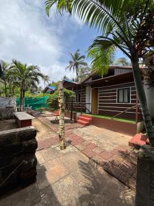 a house with a palm tree in front of it at Tapas Beach Cottage in Calangute