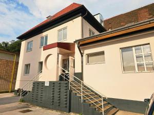 a white house with a staircase in front of it at Hostel pod gradom in Celje