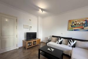 a living room with a couch and a tv at Apartamento en Puerta del mar con piscina y wifi - PUERTA DEL MAR CALAHONDA in Mijas Costa