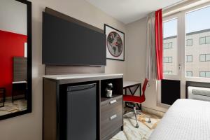 a bedroom with a flat screen tv on a wall at Ramada by Wyndham Brooklyn Empire Blvd in Brooklyn