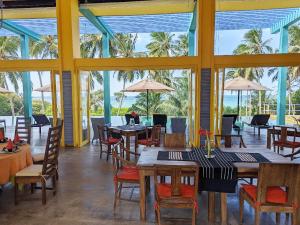 a restaurant with tables and chairs and palm trees at Buckingham Place in Tangalle