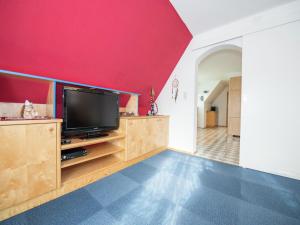 a living room with a tv and a red wall at Apartment in Tröpolach near Nassfeld Gondola in Tröpolach