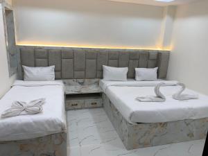 2 camas en una habitación con sábanas blancas y arcos en Sargam Palace, en Varanasi