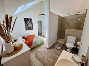 a bedroom with a bed and a toilet and a sink at La maison de MiLy in Bassenge
