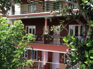 a red building with a balcony and trees at Kerala House in Thekkady