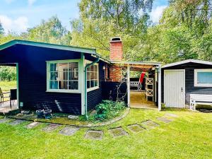 a small blue house with a porch and a deck at 4 person holiday home in Frederiksværk in Frederiksværk