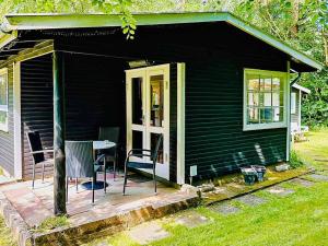 a black house with a table and chairs on a deck at 4 person holiday home in Frederiksværk in Frederiksværk