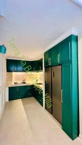 a kitchen with green cabinets and a stainless steel refrigerator at Terra Tia Boutique Villa Senggigi in Senggigi 