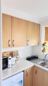 Una cocina con armarios de madera, fregadero y microondas. en Peaceful Springfield Studio, en Chelmsford
