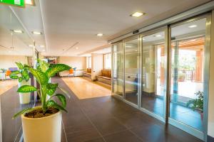 un vestíbulo de oficina con una planta en una olla grande en Hotel Residence Ulivi E Palme, en Cagliari