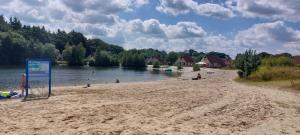 a beach with a sign in the sand and a body of water at Mooi Drenthe in Wezuperbrug