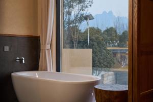 une baignoire dans une salle de bain avec une fenêtre dans l'établissement Jiuhua Mountain Tanfeng Resort Homestay 远眺山景大佛 九华山潭风民宿, à Miaoqian