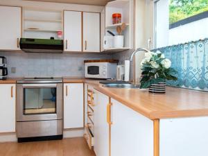 a kitchen with white cabinets and a vase of flowers on a counter at 2 person holiday home in Gråsten in Gråsten