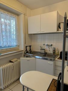 une petite cuisine avec des armoires blanches et une table dans l'établissement Wohlfühlen bei Tobi, à Gelsenkirchen