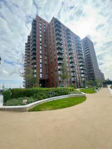 a large apartment building with a park in front of it at Wembley Cozy Cloud Waterfront Retreat with Parking near Wembley stadium in London