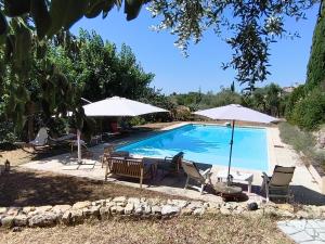 a swimming pool with two umbrellas and chairs at Chambres d'hôtes de charme La Joséline in Flayosc