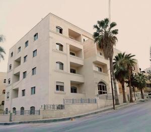 a white building with palm trees in front of it at EVANNA SUITE AND HOTELs ايفانا للشقق الفندقيه و المفروشه in Amman