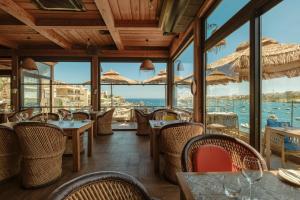 a restaurant with tables and chairs and a view of the water at Damare Resort & SPA in St. Paul's Bay