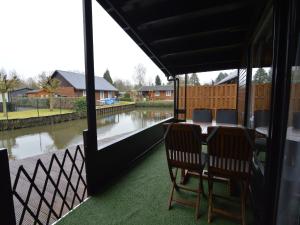 a porch with a table and chairs and a view of a river at Modern waterfront chalet in Geel