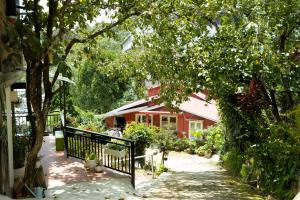 a red house with a black fence and trees at Ken's House Dalat in Da Lat