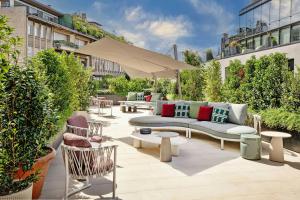 a patio with a couch and tables and an umbrella at Casa Brera, a Luxury Collection Hotel, Milan in Milan