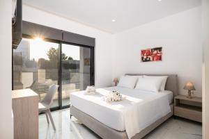 Un dormitorio blanco con una gran cama blanca y una ventana. en Icon Luxury Apartments, en (( Kermetés ))