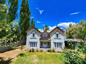 a large white house with a fence and trees at Rus Olive Lodge Skardu in Skardu