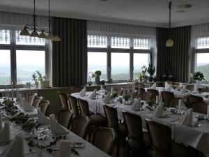 a dining room with white tables and chairs and windows at Akzent Berghotel Rosstrappe in Thale