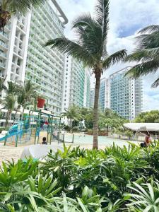 a palm tree and a playground in front of a large building at Affordable Boracay-like Staycation in Azure South in Manila