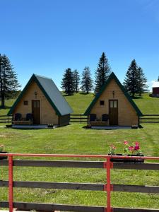 twee hutten in een veld met een hek bij Šumski raj in Žabljak