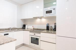 a white kitchen with white cabinets and appliances at Modern 2BR Apt with own Terrace & Pool access in Pulpí