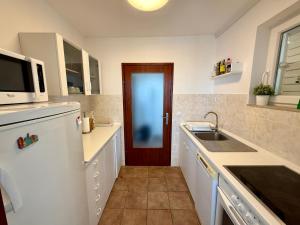 a kitchen with a white refrigerator and a red door at Apartman Val in Dramalj