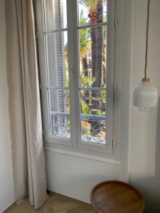 a window with a view of a palm tree at Hôtel Bon Abri - Maison Sanaryenne in Sanary-sur-Mer
