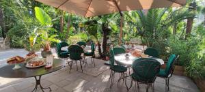 a patio with tables and chairs under an umbrella at Hôtel Bon Abri - Maison Sanaryenne in Sanary-sur-Mer