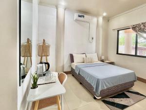 a bedroom with a bed and a desk with a phone at Casaroyal Beachfront Siquijor in Siquijor +32 photos