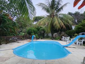a blue pool with a slide in a yard with a palm tree at Casinhas de Pipa in Pipa
