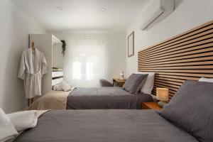 a bedroom with two beds and a robe on a dummy at Linda s Guest House Alojamento 2 in Costa da Caparica +56 photos