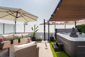 a patio with a hot tub and chairs and an umbrella at Linda s Guest House Alojamento 2 in Costa da Caparica