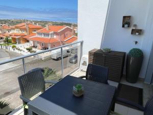 a balcony with a table and chairs and a view of a street at Stylish & Spacious Apartment with Balcony in Lourinhã