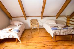 two beds in a attic room with a chair at Asher Riverside Cottages in Bonnievale