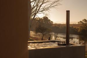 a view of a river from a window with the sun setting at Asher Riverside Cottages in Bonnievale