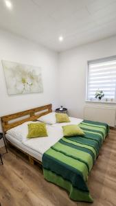 a bedroom with two beds with green and white pillows at Ferienhaus Marcali - Erholung am Thermalbad und Plattensee in Marcali